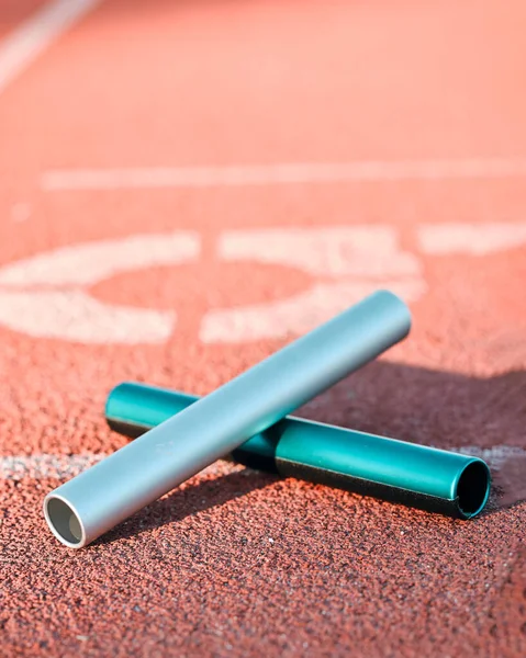 Sports, track and closeup of baton in a stadium for a relay race, marathon or competition. Fitness, running and zoom of athletic equipment on the ground for cardio training, workout or exercise