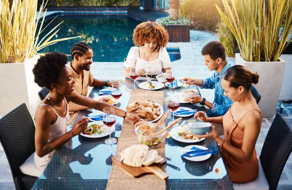 Group of friends at lunch, party in garden and happy event with diversity, food and wine for bonding together. Outdoor dinner, men and women at table, people eating with drinks in backyard in summer