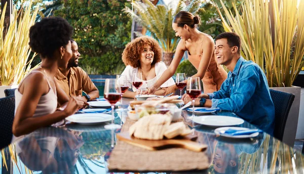 Friends, people and food outdoor on a table for social gathering, happiness and holiday celebration. Diversity, men and women group eating lunch at a party or reunion with drinks to relax in a garden.