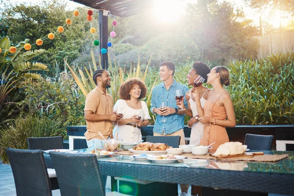 Conversation, group of friends at dinner in garden at party and celebration with diversity, food and wine at outdoor lunch. Chat, men and women at table, fun people with drinks in backyard together