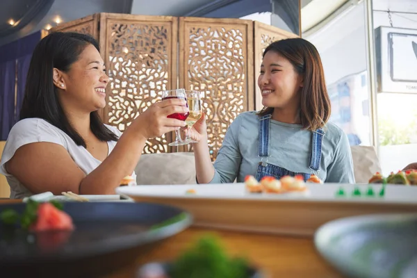 Japanese women, restaurant and toast with sushi, smile and congratulations with fine dining, party or thinking. Asian friends, happy and success with fish, alcohol or relax in diner, wine and thanks.