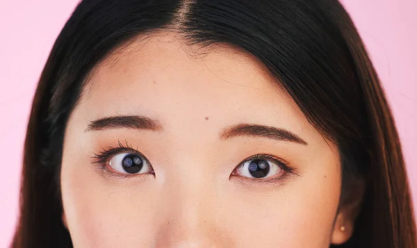 Closeup, eyes and portrait of an Asian woman on a pink background for makeup or microblading. Face, skincare and a girl or model isolated on a backdrop for facial cosmetics, foundation or eyeliner.