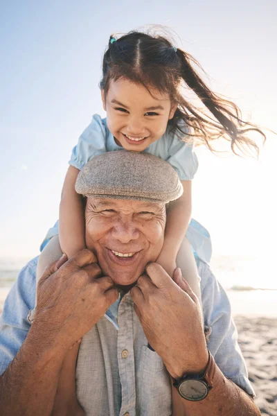 Beach, old man and kid on back happy for family travel, play outdoor together and bonding with love and fun. Vacation, elderly person smile and portrait of girl child on holiday on piggyback by ocean.