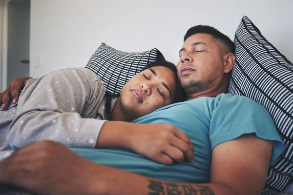 Couple, sleeping and hug together in bed to relax, rest and cuddle in marriage, relationship or love for partner in morning. Tired, man and woman dreaming with peace in home, house or bedroom.