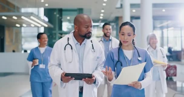 病院ロビーのタブレットで話し 医師と看護師は チーム手術 報告書 保険書類のアドバイスをします 医療情報やケアについての会話でチームワーク 黒人男性 — ストック動画