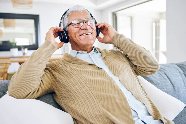老年人 在家里听音乐 客厅和休息沙发上休息 收音机或声音 带耳机和移动技术的流媒体 爵士歌曲和音频 — 图库照片