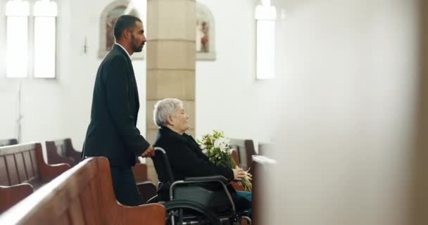 老年妇女 鲜花和教堂的丧礼用轮椅 男人和帮手手挽手 因悲伤 悲伤及被棺材压垮而在庙宇中的照顾者 花束及残疾长者 — 图库视频影像