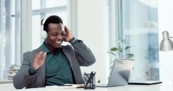 成功に満足しながら オフィスのヘッドフォンでラップトップで祝い ビジネスマンやダンスを祝います アフリカの起業家は 目標達成 インターネットの勝利またはオンラインボーナスのために音楽を聞いています — ストック動画