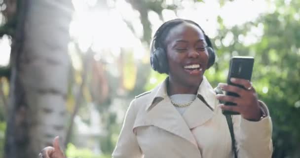 黑人女人 电话和舞蹈在公园里听音乐 放松一下 享受外面的音乐和音乐 在自然界中 快乐的非洲女性在耳机上走着 听着音轨 播客或收音机 — 图库视频影像