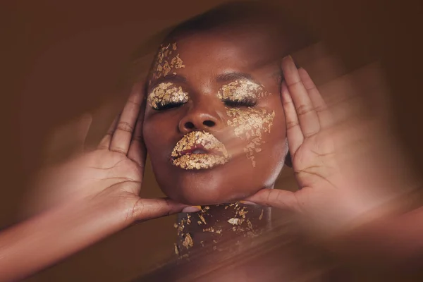 Gold beauty, makeup and black woman face with blur in studio with glitter cosmetics and sparkle art. Brown background, African female model and shine from paint and glow with golden luxury treatment.