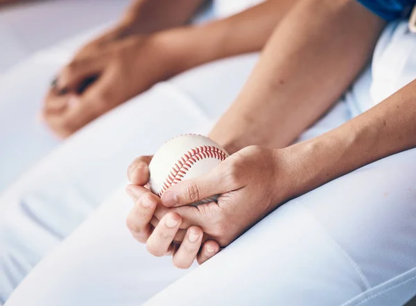 Hands, sports and baseball with a player in a dugout, waiting during a game of competition closeup. Ball, ready and uniform with an athlete holding equipment for a match in a stadium or venue.