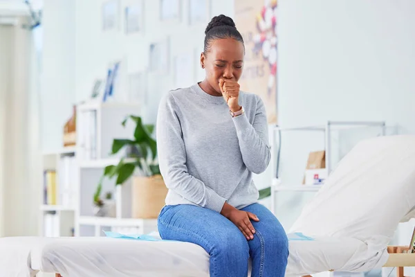 Black woman, sick and throat infection on bed at hospital waiting for doctor in checkup, visit or appointment. Frustrated African female person or patient with sore neck, virus or cough at the clinic.