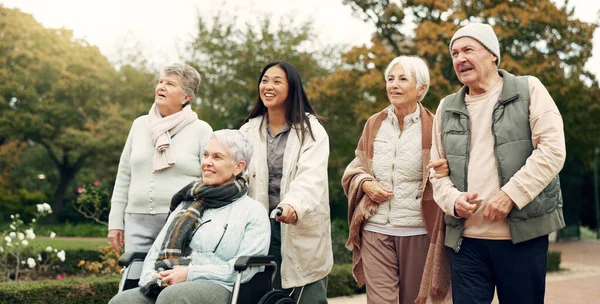 Friends, walking and elderly people in park for bonding, wellness and quality time together outdoor. Friendship, health and senior man and women with caregiver in nature for fresh air, calm and relax.