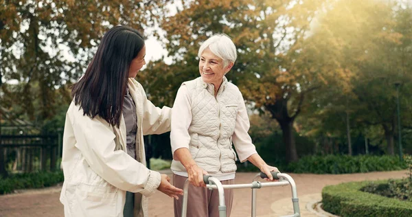 Park, walker and woman help senior walking as support, trust and care for morning healthcare exercise or workout. Health, physical therapy and elderly with caregiver for outdoor rehabilitation.