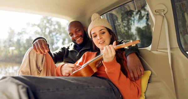 Singing with Guitar, winter and a couple in a car for a road trip, date or watching the view together. Happy, travel and back of a man and woman with an affection in transport during a holiday or cam.