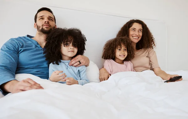 Bedroom, kids and parents watch television series, subscription movies or streaming morning video, media or entertainment. Home bed, relax family or happy mother, father and children watching tv show.