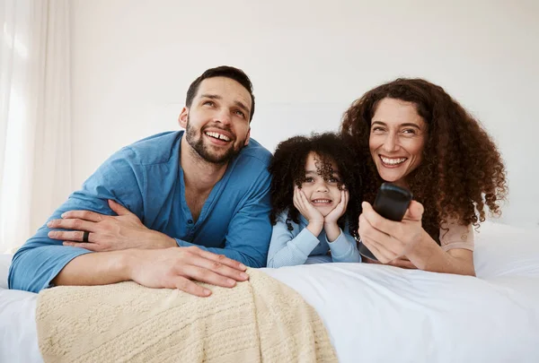 Bedroom, happy family child and parents watching tv series, movie or streaming online video, cinema or theatre together. Bed, home and relax mom, dad and kid watch cartoon show, television or film.
