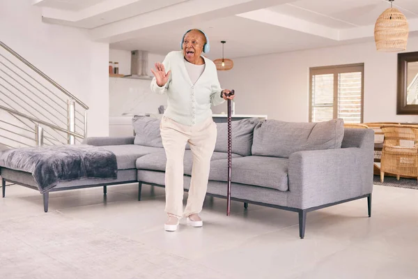 Living room, dancing and happy senior woman with headphones enjoy music and excited for retirement in her home. Happiness, freedom and elderly person listening to radio, audio and song with smile.