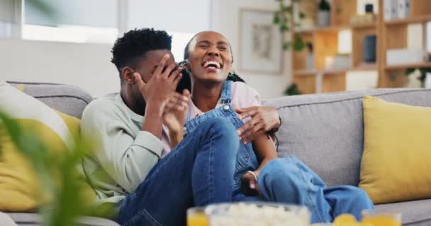 ホラー カップルは ソファーでテレビを見ているハグし 幸せで遊び心があります テレビ シリーズや映画をストリーミングしながらリビングルームボンディングで怖い黒人女性を受け入れる — ストック動画