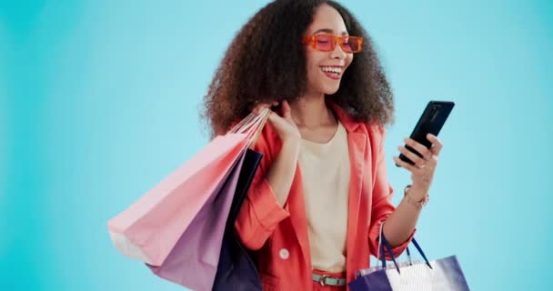 女人与购物袋和电话时尚孤立在蓝色背景的模拟空间工作室 礼物和带着太阳镜的非洲客户 在社交媒体上销售电子商务 — 图库视频影像