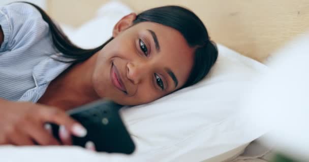 放松和一个女人在床上为社交媒体 在线聊天或通知电话 早上和一个年轻的印度女孩 带着一个应用程序的手机 阅读通信或在家里打字 — 图库视频影像