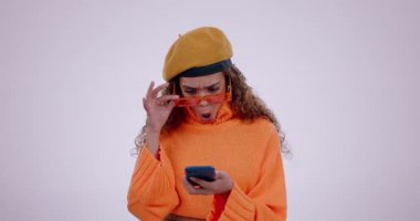 Sürpriz, şık ve beyaz arka planda telefonu olan bir kadın iletişime tepki veriyor. Moda, gençlik ve sohbet okuyan bir kız ya da cep telefonunda 