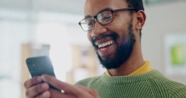 Telefon, gülümseme ve sosyal medya. İş yerinde çalışırken siyahi bir adam bir mim 'e gülüyor. Yüz, iletişim ve cep telefonundaki mesaja bakan mutlu genç bir çalışan..