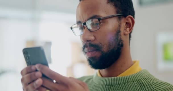ハッピー ソーシャルメディア 黒人の男が仕事で仕事をしている間にミームで笑っている モバイルでテキストメッセージを見ている若い従業員との顔 コミュニケーション — ストック動画