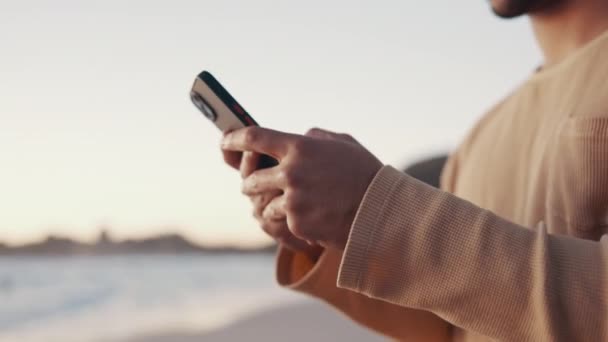 ビーチ およびソーシャルメディア モバイルアプリ ウェブサイトにテキストメッセージを入力する手のクローズアップ テクノロジー オンラインおよび男は休暇 休日または旅行で海によって携帯電話でインターネットでスクロールします — ストック動画