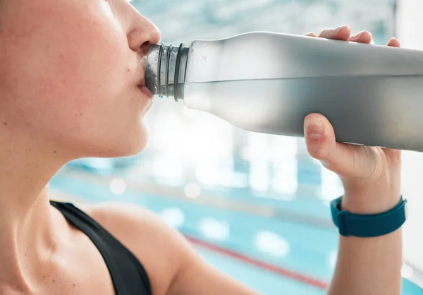 Swimmer, bottle or woman drinking water to relax on break after exercise, workout or fitness training. Hydrate, closeup or sports girl athlete with liquid for wellness or health by swimming pool.