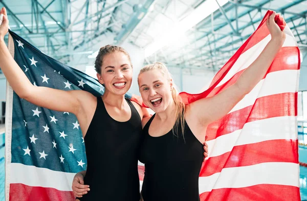 Athlete women, american flag and celebration for win, fitness or excited smile in portrait at sports contest. Girl team, winner and hug by swimming pool for success, exercise and goals at competition.