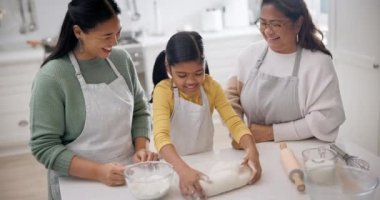 Yemek pişirme, yemek ve aile mutfakta öğrenme, gülümseme ve anneyle yemek pişirme konusunda yardımcı oluyor. Mutlu, gülen ve destek olan anne, genç kız ve büyükanneyle birlikte bir evde un..