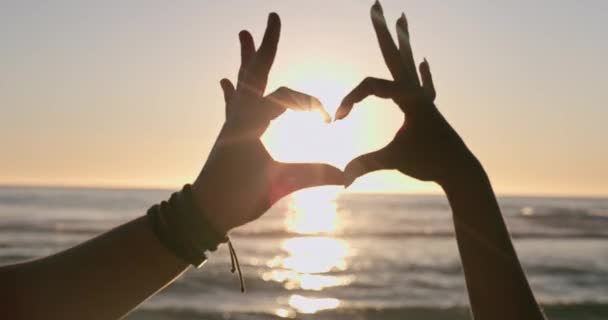 心和手在夕阳的沙滩上为爱情 关怀和浪漫的假日 假期和夏日的耀斑而手牵手 海上服装 人和手指头的轮廓 以求得支撑 自由或情感符号 — 图库视频影像