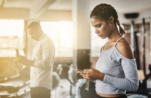 Fitness, gym and woman with a phone for communication, internet and workout app. Serious athlete person with a smartphone for texting, influencer post or online for wellness and health space or flare.