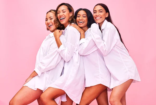 Women, friends and portrait in studio with natural beauty, diversity and white shirt with laugh. Pink background, bonding and young female group together with inclusion, happy smile and wellness.