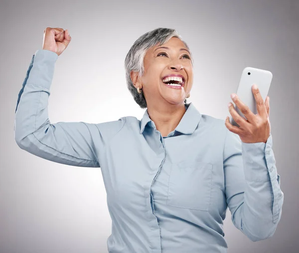 携帯電話 そしてスタジオのシニア女性がオンラインベット 良いニュース 賞を受賞しました ハッピー お祝い そしてグレーの背景で隔離された電話で成功するためのフィストポンプ付きの高齢女性モデル — ストック写真