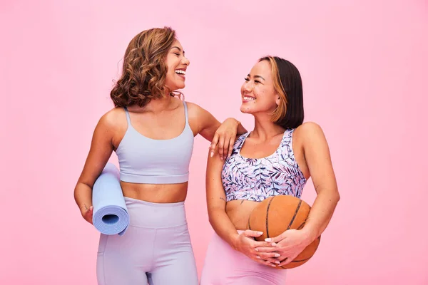 Sports, fitness and women on pink background for yoga, training and exercise with ball and yogi mat. Friends, happy and people in studio with gym equipment for wellness, workout and healthy body.
