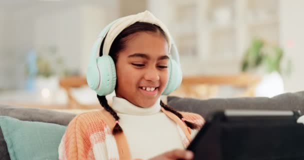 Kız Çocuk Kulaklıklı Bir Tablet Bilgisayar Oyunları Için Kanepeye Oturmuş — Stok video