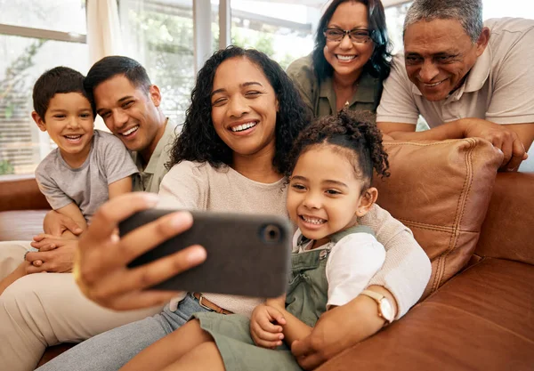 stock image Big family, selfie and grandparents with children on sofa for holiday, love and relax together at home. Interracial people, mother and father with kids smile on couch for profile picture photography.