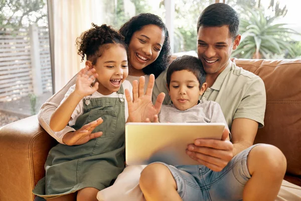 Tablet, video call and family with wave, greeting and smile on a living room sofa at home. Mother, dad and children together with online communication of parents and kids with discussion on web app.