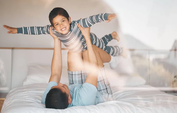 Kid, father and smile on bed for airplane games, support and relax at home for crazy fun. Portrait, dad and boy child excited to fly in bedroom for freedom, fantasy or balance of play, care or energy.