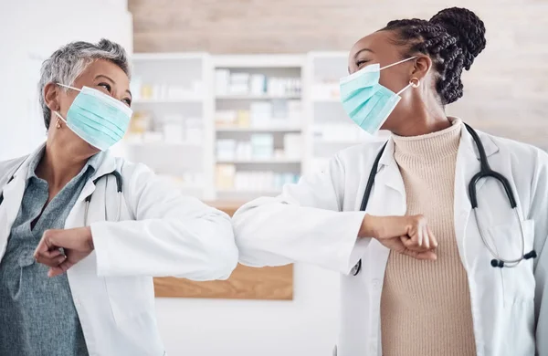 People, doctor and face mask in elbow greeting, meeting or handshake in social distancing at hospital. Women, medical or healthcare team touching arms in regulations, pandemic or health and safety.