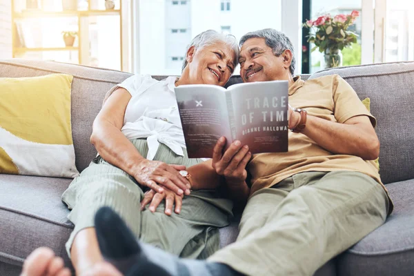 Senior, relax and a couple reading a book on the sofa for learning together. Smile, love and an elderly man and woman with a novel or story on a home living room couch for knowledge in retirement.