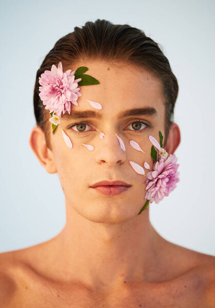 Floral, skincare and flowers with portrait of man in studio for beauty, natural cosmetics and creative. Glow, self love and spring with face of model on white background for makeup, spa and wellness.
