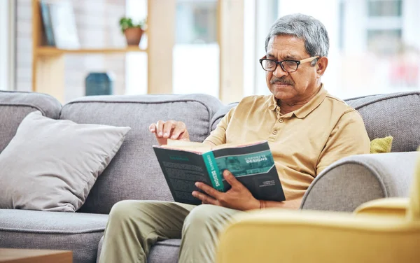 Home, relax and senior man with a book, retirement and calm with a story in a living room. Old person, calm and pensioner in a lounge, novel or literature with a hobby, self help or reading on a sofa.