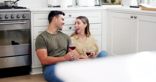 新しい家を祝うためにワイン 歓声と笑顔でキッチンで床にハッピーカップル ガラスでアルコールと乾杯 リラックスしてアパートでの会話 — ストック動画