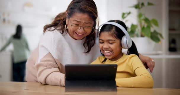 在家人探访的时候 带着餐具 耳机和一个和奶奶一起在家里客厅里笑的女孩 与资深女性和孙女一起浏览社交媒体的科技 迷因或游戏 — 图库视频影像