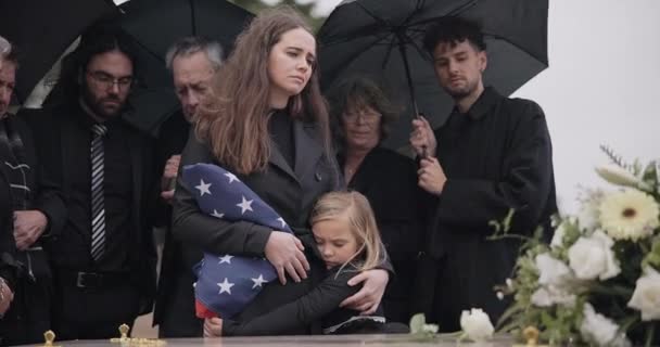 葬礼上 家人和悲伤的人举着美国国旗 悲痛和哀悼着死亡 丧葬和丧偶的寡妇在离别活动中沮丧不已 母亲和团体在棺材 棺材前聚会 并在仪式上哭泣 — 图库视频影像