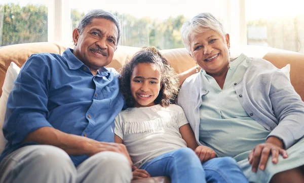 Grandparents, portrait and happy child on sofa in home living room, bonding and having fun together. Smile, grandma and grandfather with kid in lounge to relax with love, care and family connection.