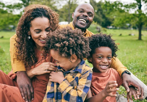 Happy black family, parents and children in a park in summer, smile and relax on grass field for love and fun in nature. Happiness, picnic and portrait of African people outdoor and playing together.